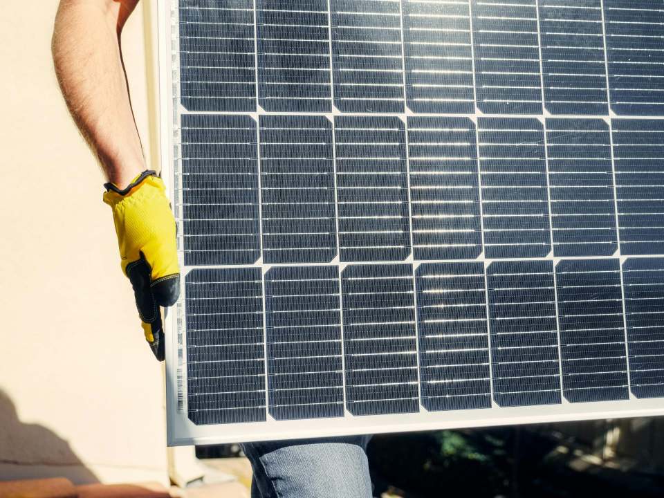 Primer plano de una persona instalando un panel solar al aire libre bajo la luz del sol.